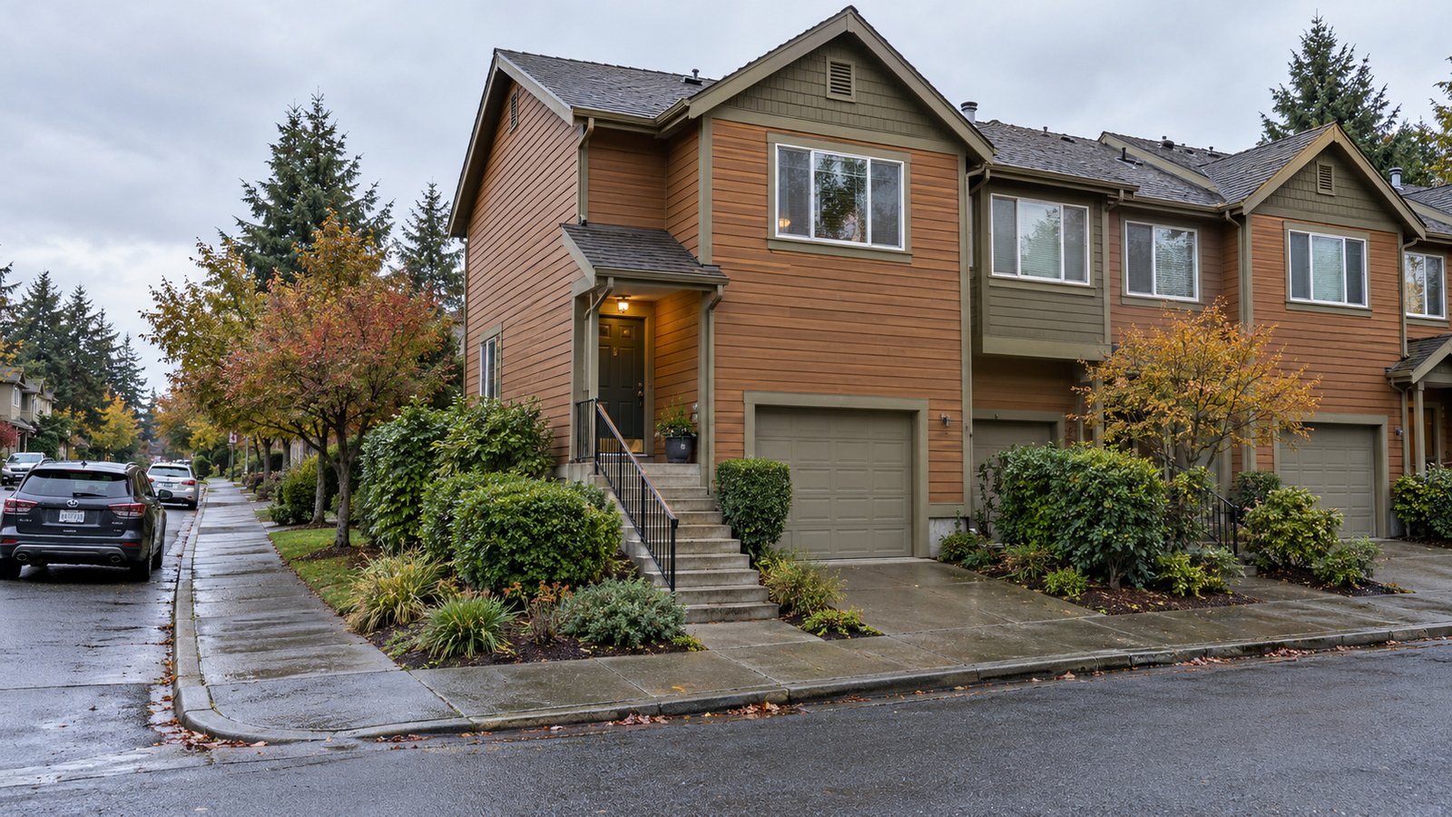 A cedar-sided Seattle-style end-unit townhouse with front steps beside a garage driveway. A cedar-sided Seattle-style end-unit townhouse with front steps beside a garage driveway.