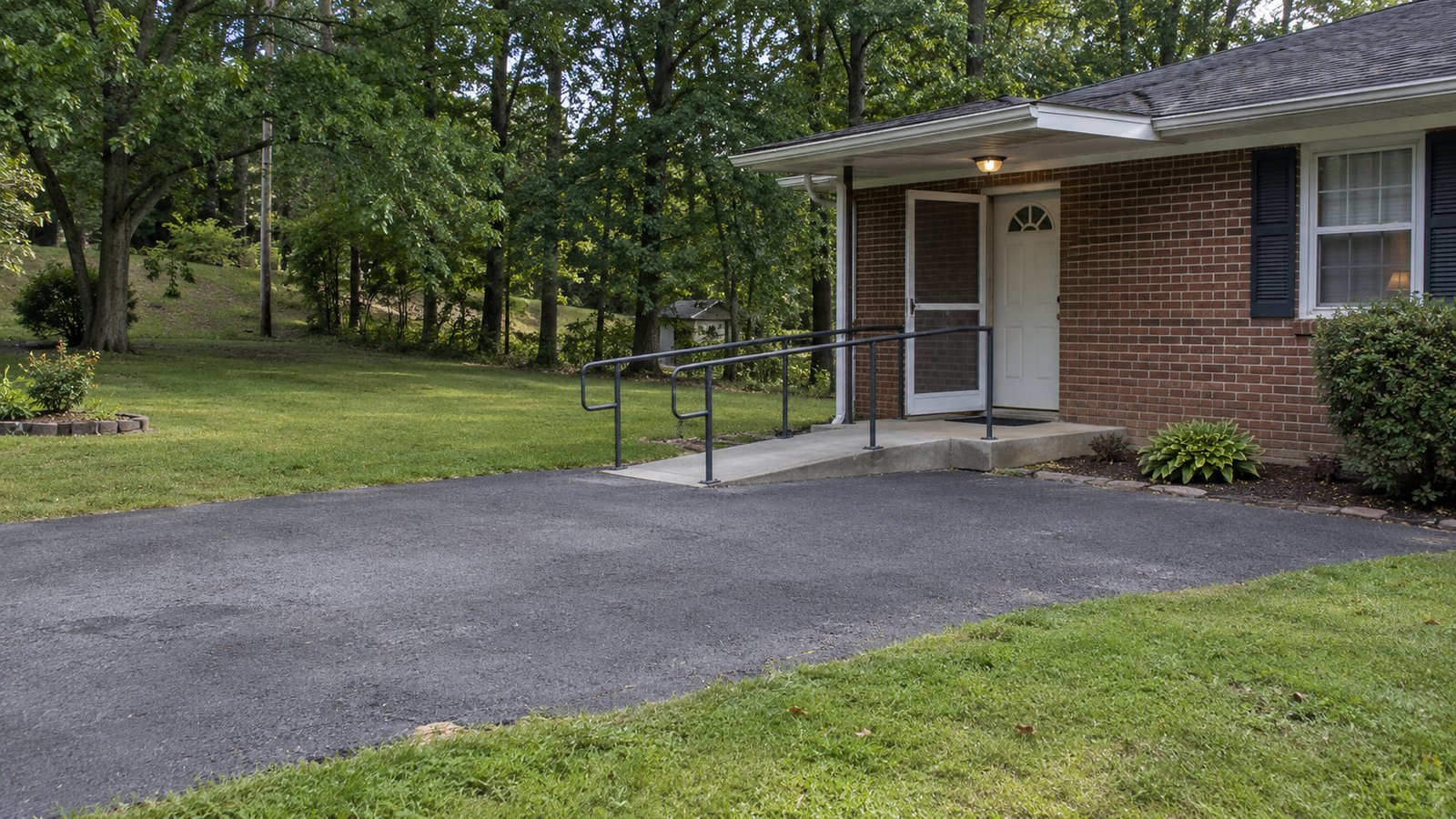 Inspect the receiving entrance A complete shallow concrete ramp with both handrails and a brick-house doorway.