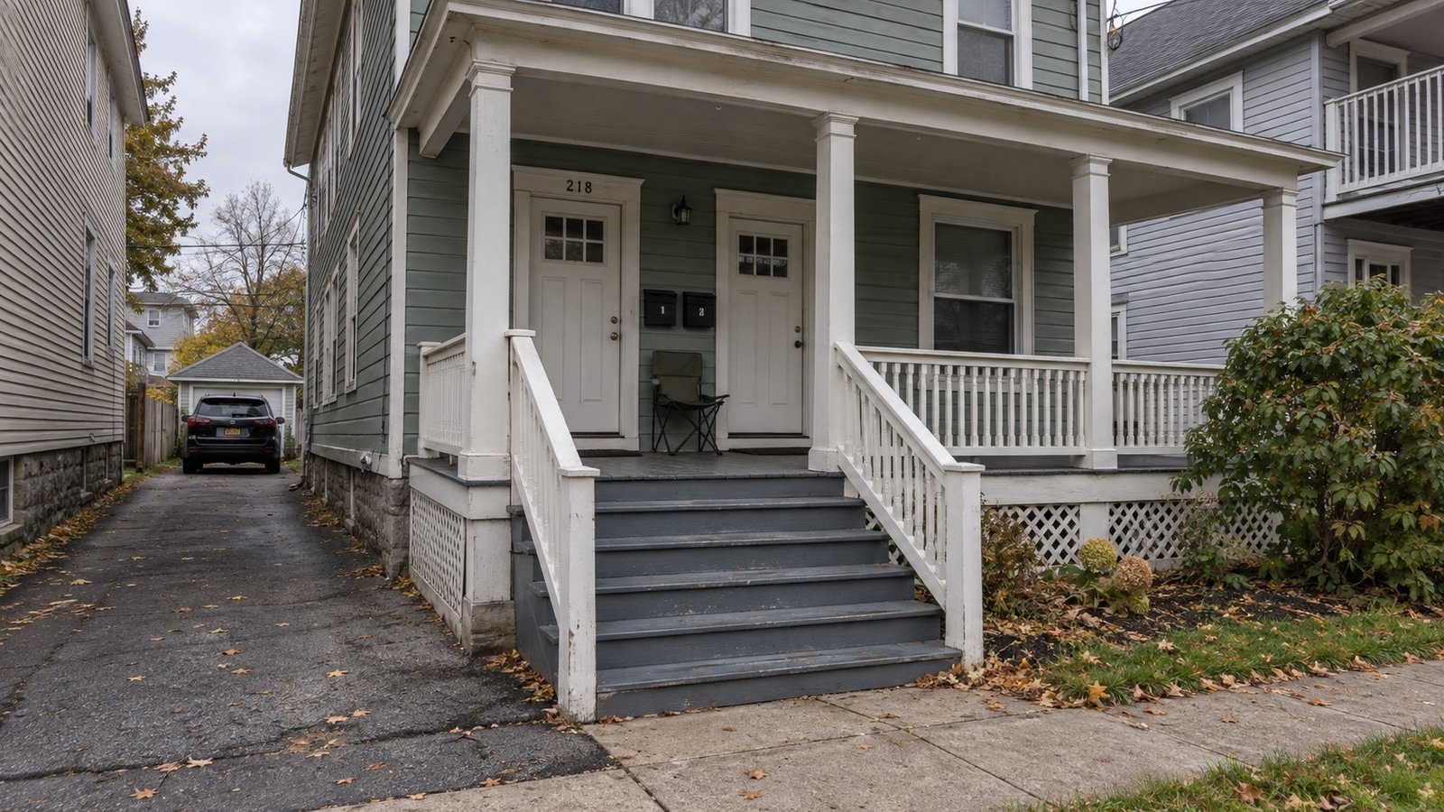 An older two-flat house with a shared porch and a narrow driveway.