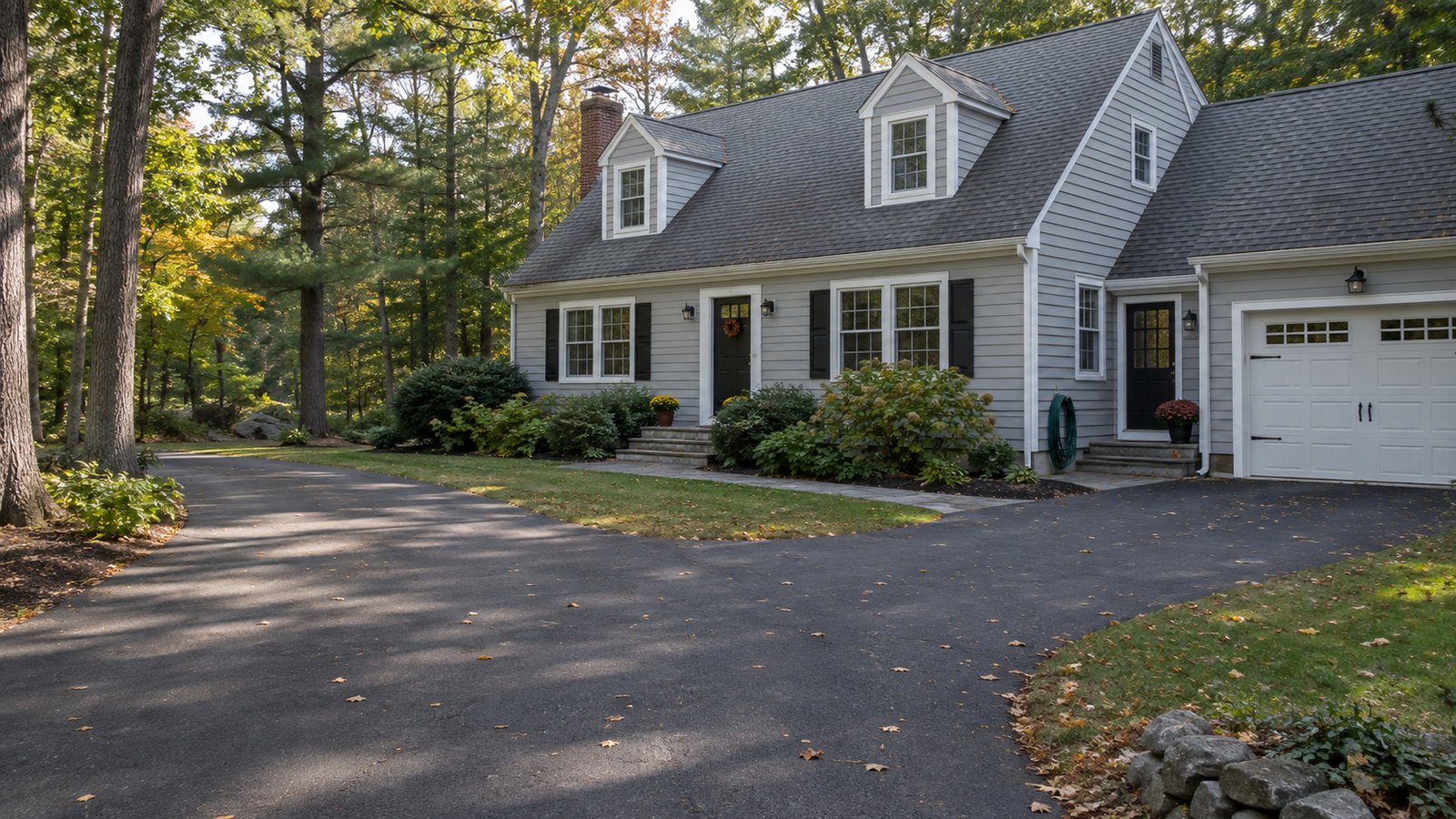 Planning a Tolland residential move Cape-style house beside a wooded paved driveway and attached garage