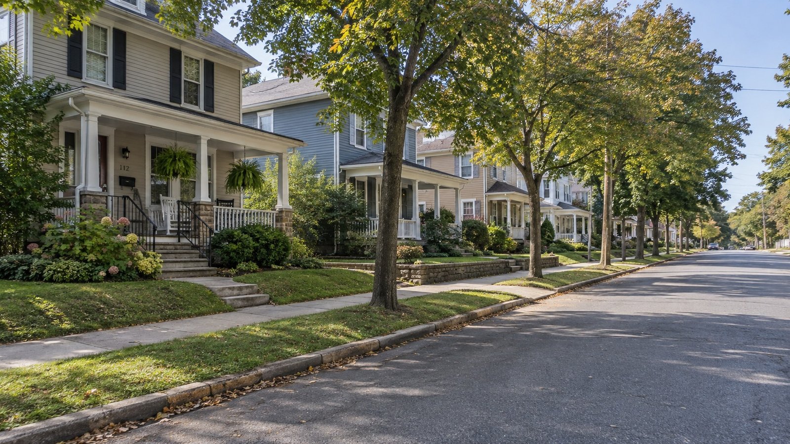 A residential street Illustrative American residential street with porches, small front yards, trees and a sidewalk.