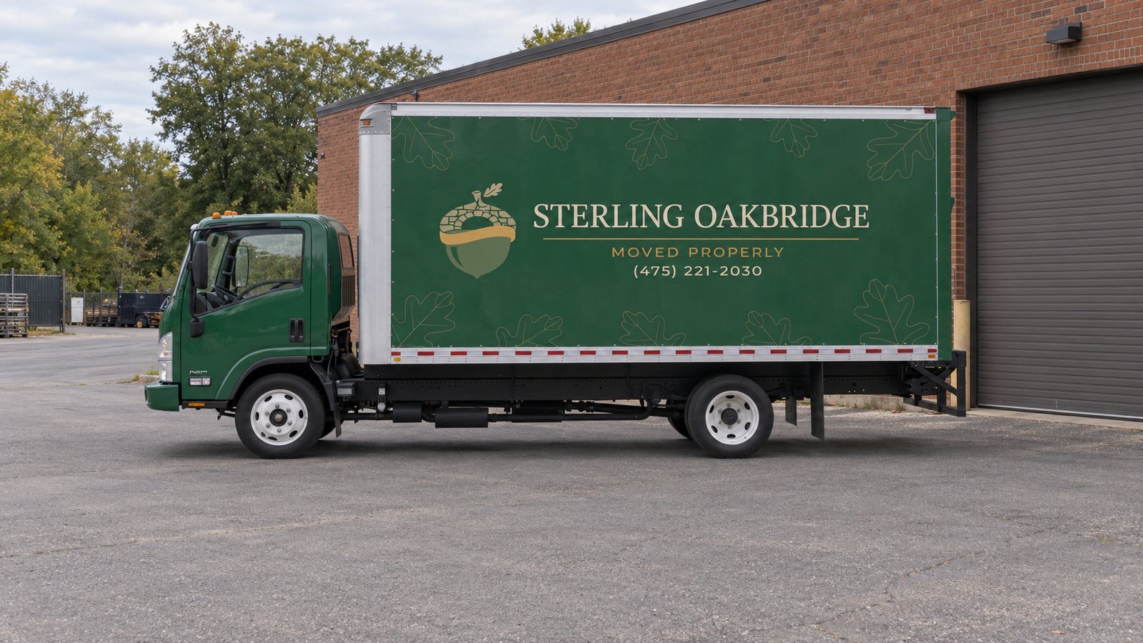 Review the vehicle position A complete green Sterling Oakbridge Isuzu NPR20 parked on a private paved court beside a brick warehouse.
