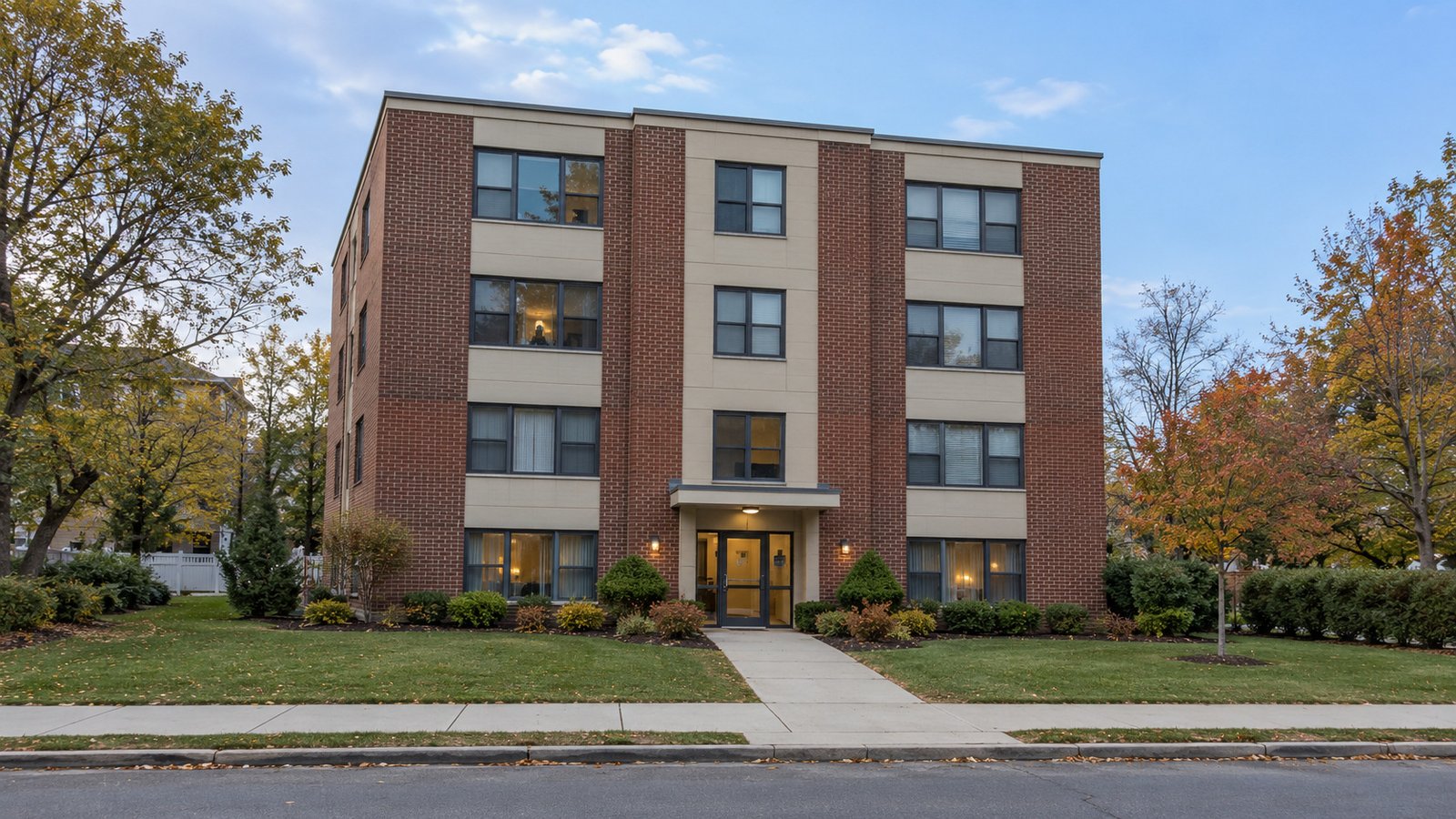 Complete four-storey brick apartment building with a glass entrance, level private walk and public sidewalk, with planting outside the route.