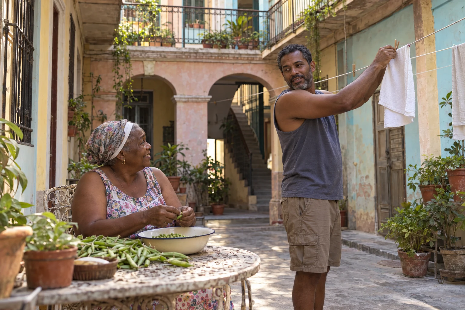 Family life through an ordinary Havana courtyard task A woman shells peas into a bowl while a man fastens a towel to a clothesline in a planted courtyard.